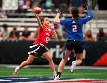 A defender rushing the quarterback who is throwing the ball in a girls flag football game.