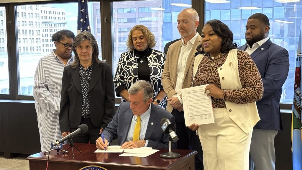 John Carney and members of city council pose for photos following bill signing