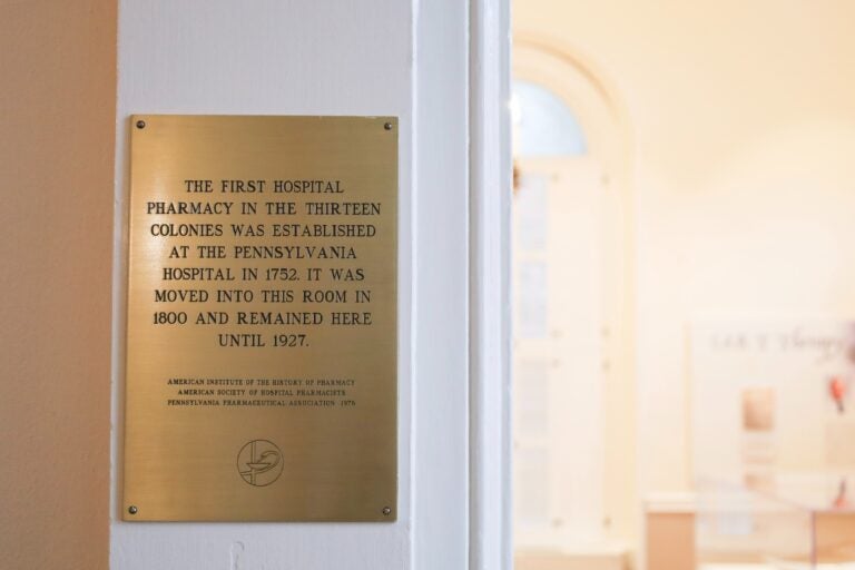 a plaque reads THE FIRST HOSPITAL PHARMACY IN THE THIRTEEN COLONIES WAS ESTABLISHED AT THE PENNSYLVANIA HOSPITAL IN 1752. IT WAS MOVED INTO THIS ROOM IN 1800 AND REMAINED HERE UNTIL 1927.