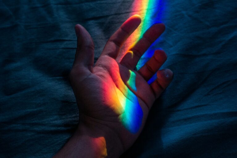 An open palm hand with four colored light shinning on it —red, yellow, green and blue.