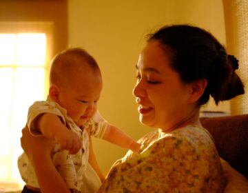 A mother is smiling while holding a newborn baby.