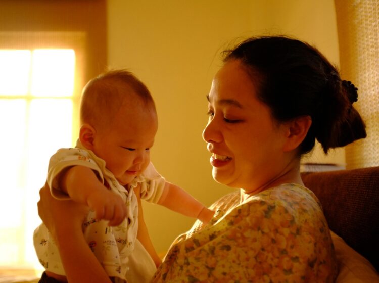 A mother is smiling while holding a newborn baby.