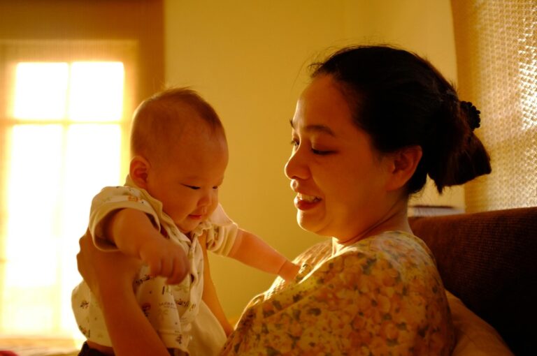 A mother is smiling while holding a newborn baby.