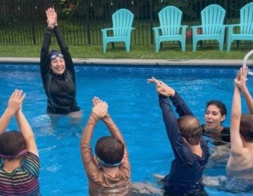 Jennifer May is teaching a swimming lesson in the pool to children.