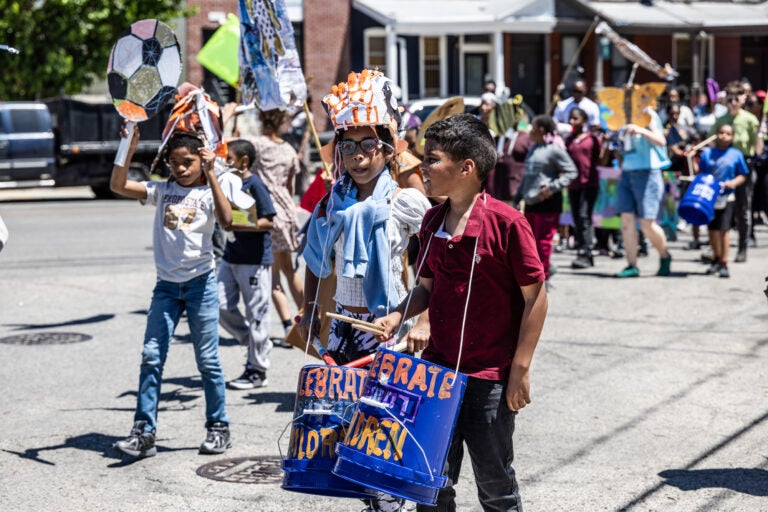 School children have a parade with their large puppets and signs.
