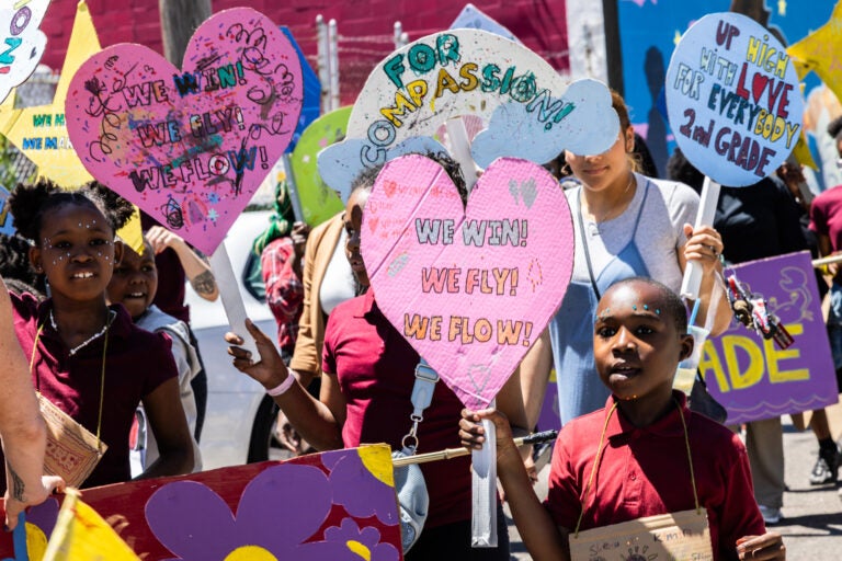 School children have a parade with their large puppets and signs.