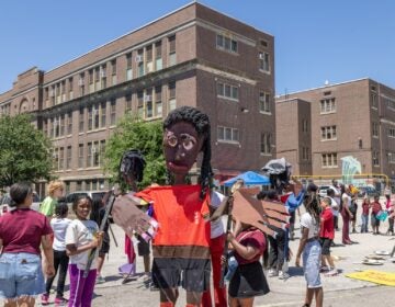 School children have a parade with their large puppets and signs.