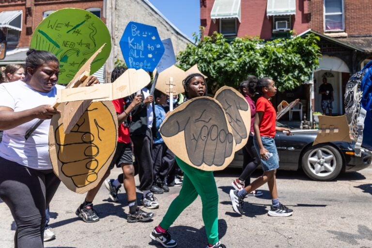 School children have a parade with their large puppets and signs.
