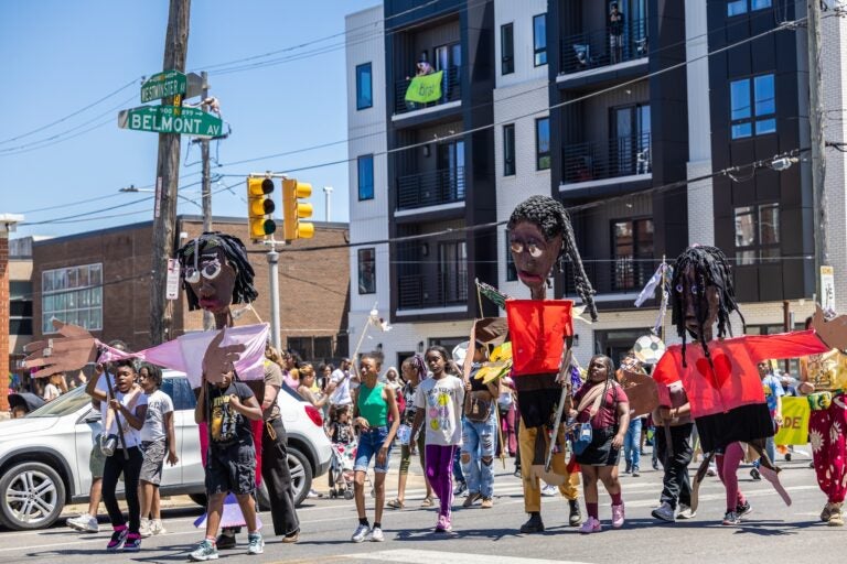 School children have a parade with their large puppets and signs.