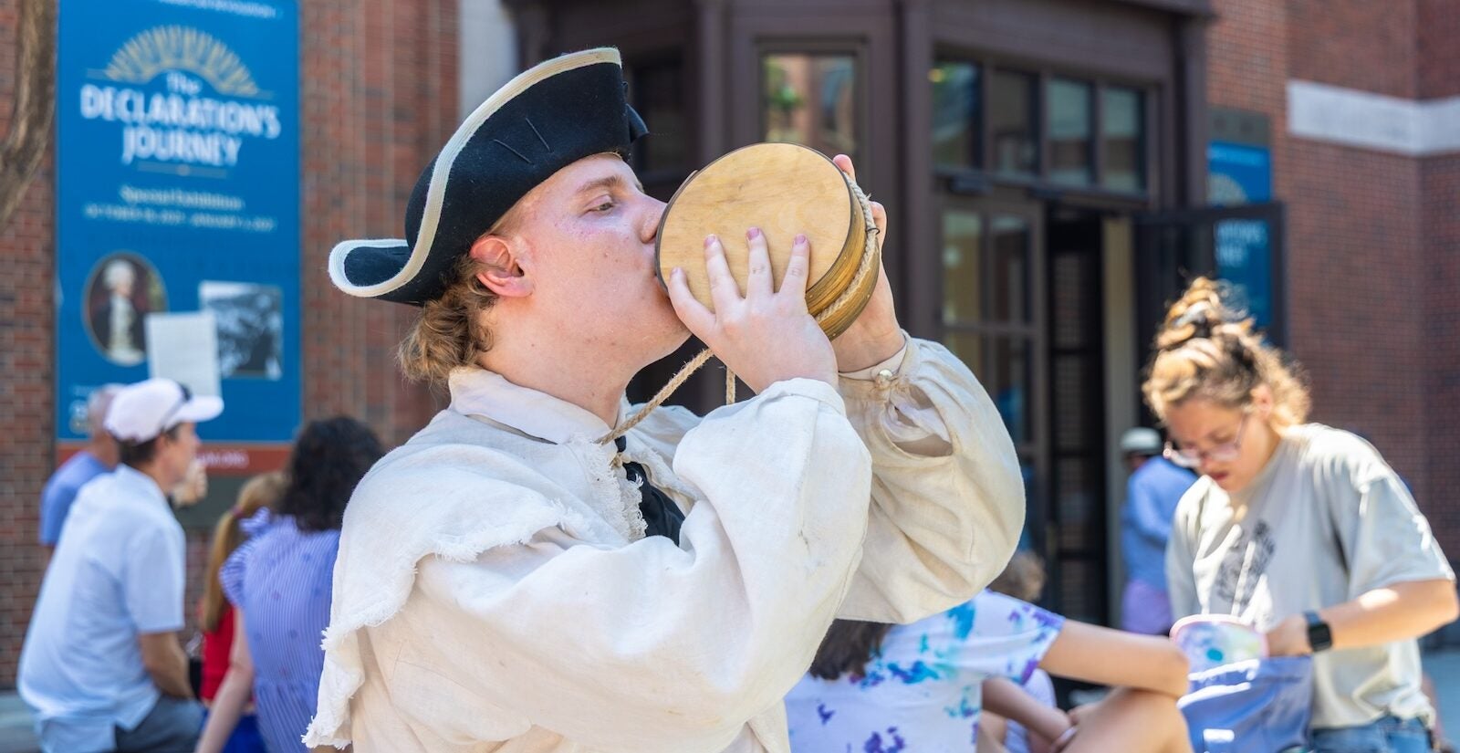 Robert Buza, dressed in Revolutionary War attire, drinks out of a canteen during extreme heat outside of the Museum of the American Revolution on July 3, 2026