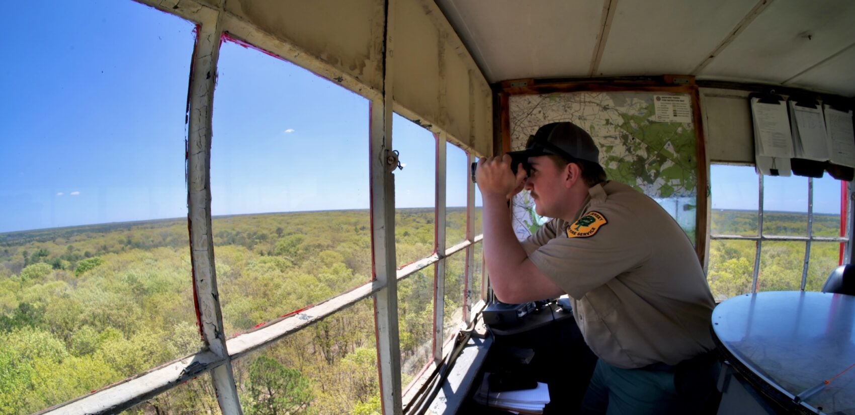 Brian Gerber looks out from the Medford Fire Tower through binoculars.