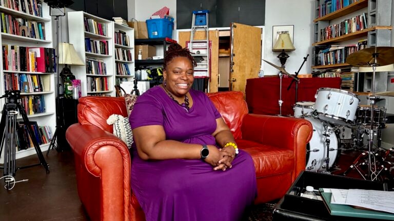 Kendrah Butler-Waters poses for a photo on a red couch in her studio.