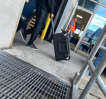 A man wheels a suitcase through an airport.