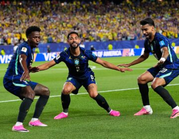 Three Brazil players celebrate after a goal.