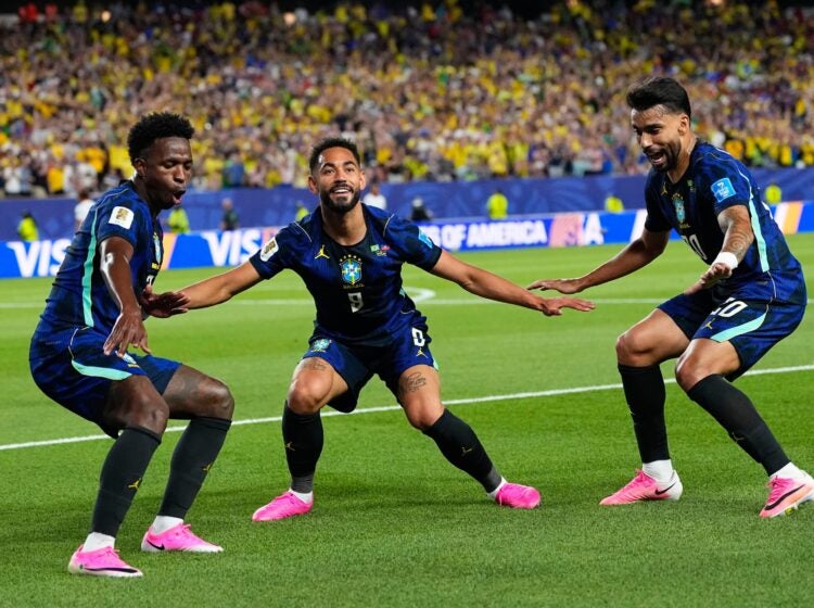 Three Brazil players celebrate after a goal.