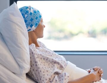 Young woman in bed suffering from cancer. Thoughtful woman battling with tumor looking out of window (Rido81/Bigstock)