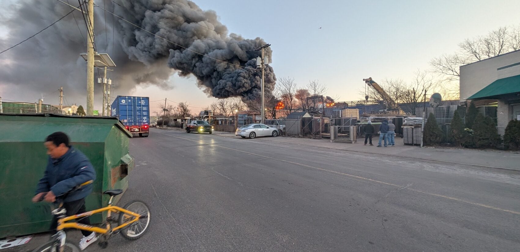 A person walks their bike away from the blaze at the EMR facility.