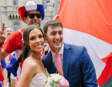 Newlyweds posing for a photo while a Croatia fan crashes the picture behind them.