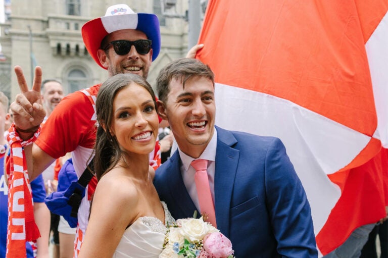 Newlyweds posing for a photo while a Croatia fan crashes the picture behind them.
