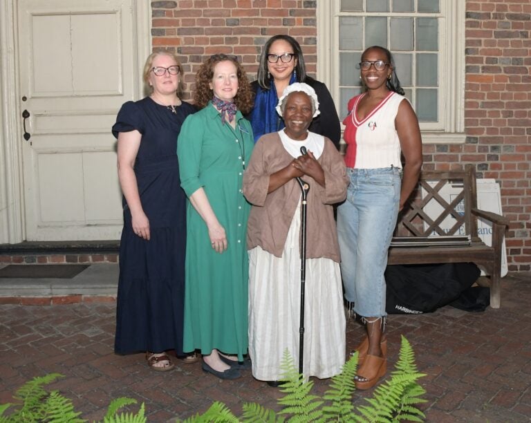 Five women pose for a photo together outside of the historic house.