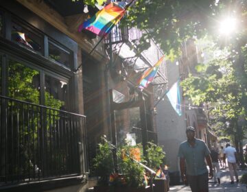 gayborhood-h-kwon-bp-2026-06-16-1 Pride flags hang from apartment buildings on a city street.