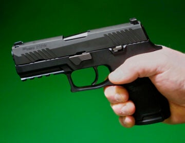 A Sig Sauer P320 handgun is held by a Maine gun shop owner, Tuesday, June 17, 2025. (AP Photo/Robert F. Bukaty)