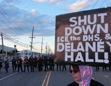 A protester holds a sign that says, ''Shut down ICE, the DHS, and Delaney Hall!'' as law enforcement officers stand outside Delaney Hall detention center Sunday, May 31, 2026, in Newark, N.J.