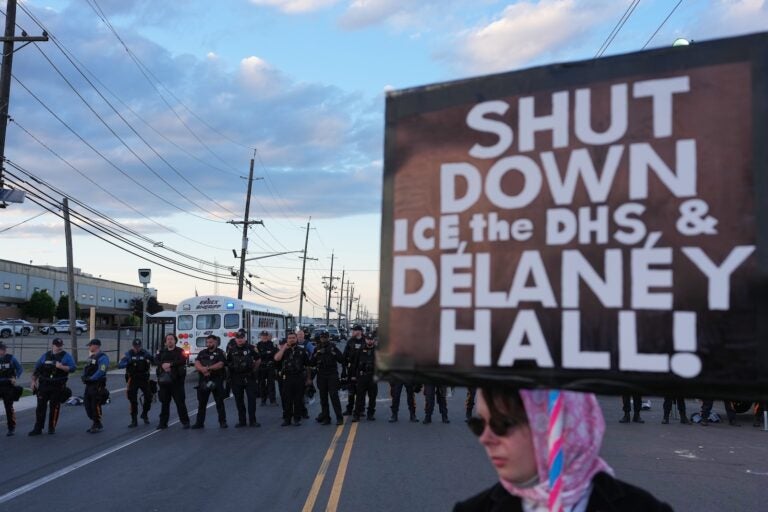 A protester holds a sign that says, ''Shut down ICE, the DHS, and Delaney Hall!'' as law enforcement officers stand outside Delaney Hall detention center Sunday, May 31, 2026, in Newark, N.J.