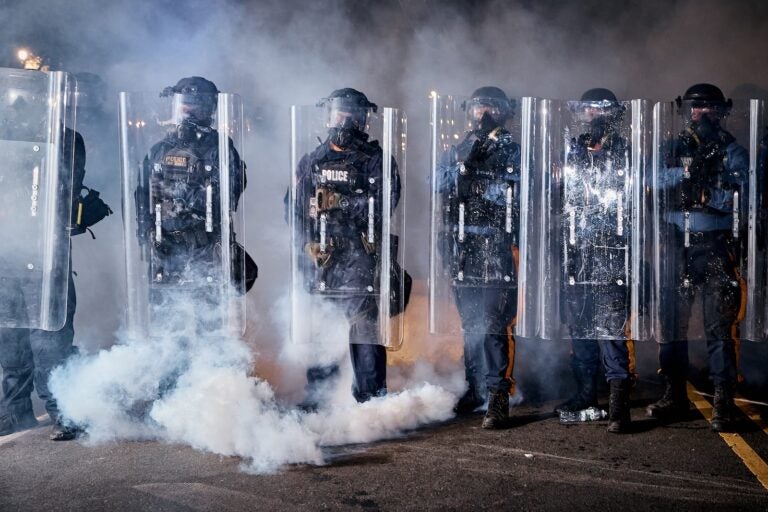 State police officers stand behind shields as tear gas fills the area outside the Delaney Hall detention center during a protest against the transfer of detainees and federal immigration policies, Friday, May 29, 2026, in Newark, N.J.