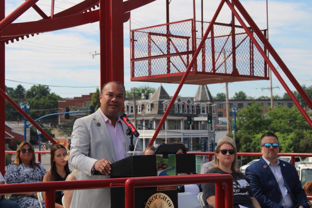 Phoenixville Mayor Peter Urscheler speaks from a podium with a ferris wheel in the background