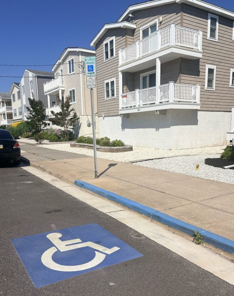 A handicapped parking spot in front of beachfront homes.