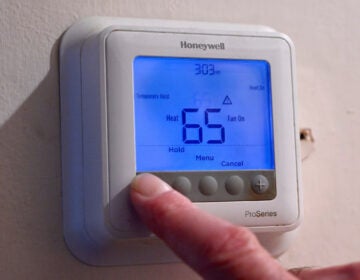 A man adjusts his thermostat