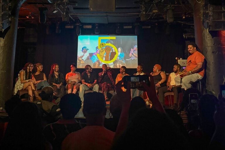Many people sitting in chairs on a stage in front of an audience for a Q and A session.