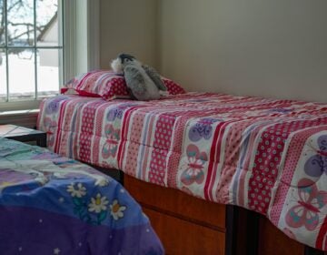 2 children's beds are seen in a bedroom.