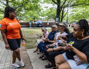 Samantha Whitfield, the Mayor of Willingboro, (in orange) chats with Patricia Lindsay-Harvey (second from the left), the President of Willingboro Community Development Corporation and her family