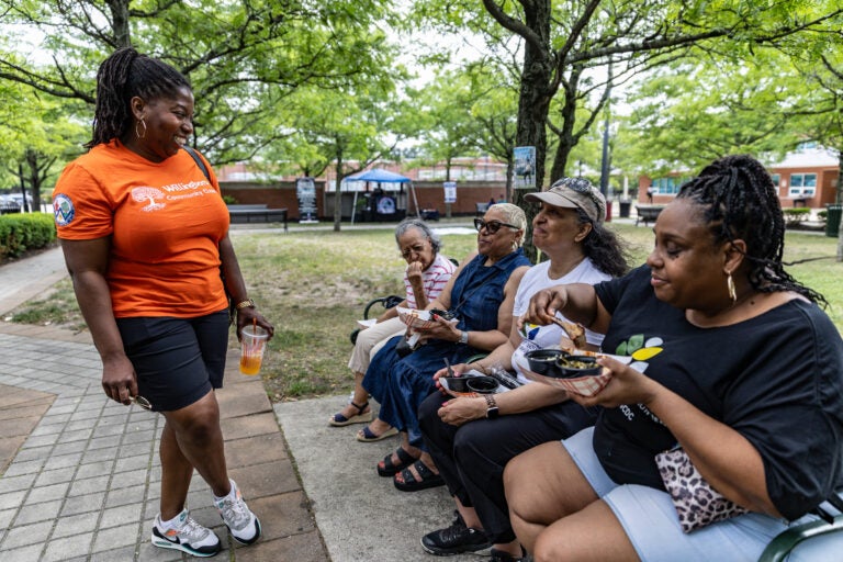 Samantha Whitfield, the Mayor of Willingboro, (in orange) chats with Patricia Lindsay-Harvey (second from the left), the President of Willingboro Community Development Corporation and her family