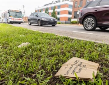 A paper bag littered by the road in South Philadelphia. (Kimberly Paynter/WHYY) A paper bag is discarded next to a busy road.