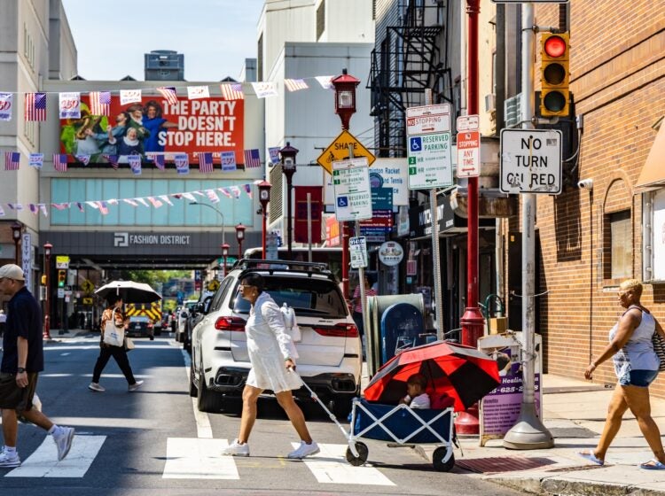 People walking across a busy intersection in Philly's Chinatown neighborhood