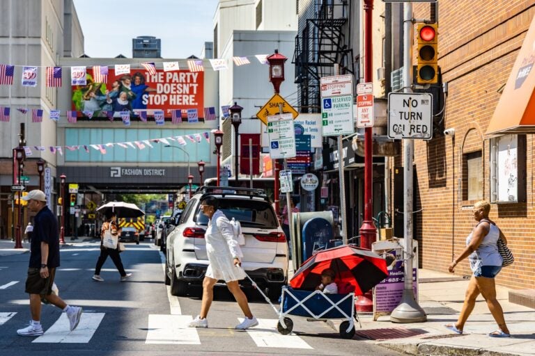 People walking across a busy intersection in Philly's Chinatown neighborhood