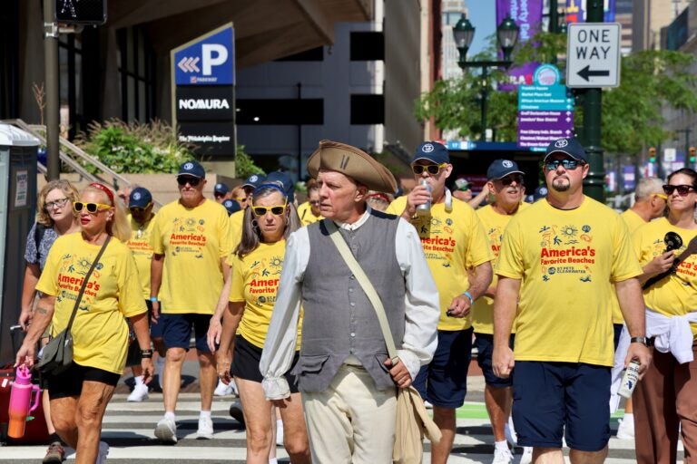 A historic reenactor leads a tour group across Sixth Street at Market to Independence Mall.
