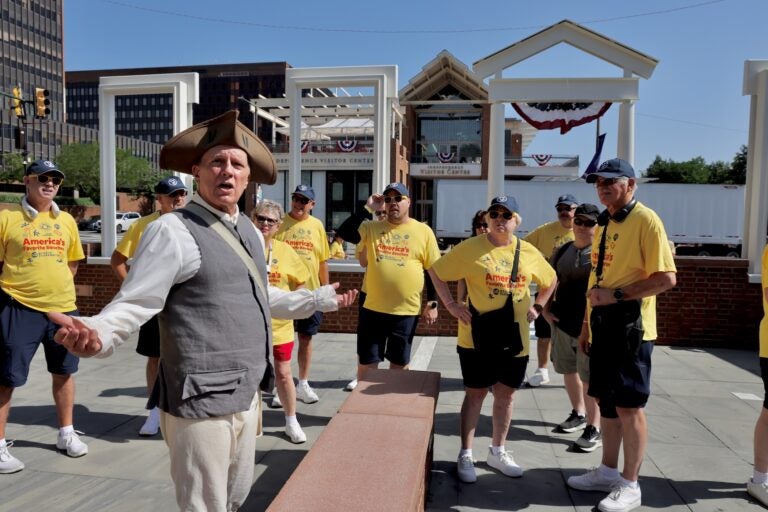 A historic reenactor leads a tour group through the President's House slavery exhibit at Sixth and Market streets.