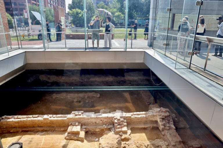 People looking down into the below-ground ruins of the President's House.