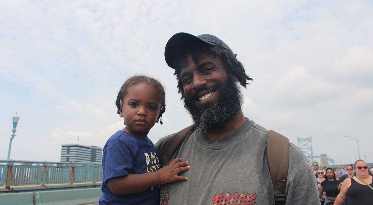 A man holds his infant son while smiling for a photo
