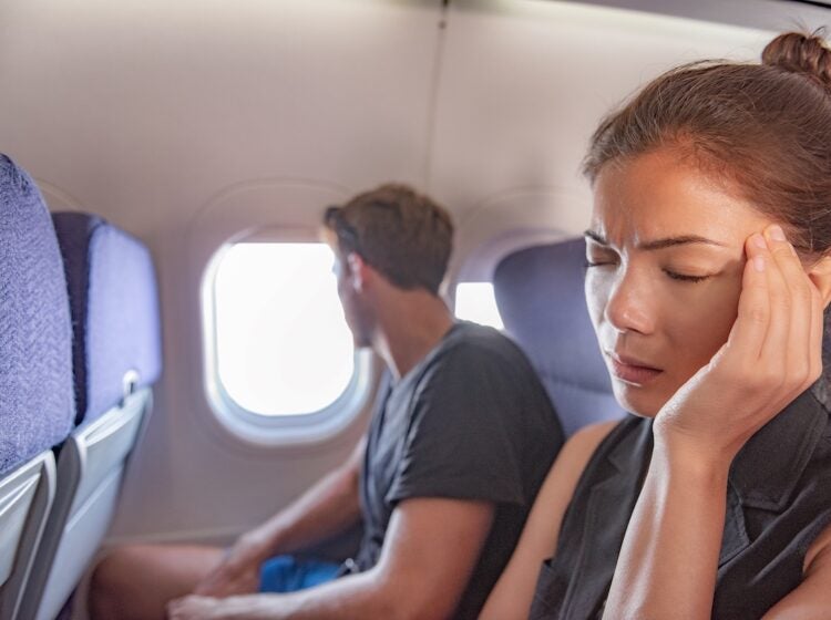 Sick woman on airplane with headache.