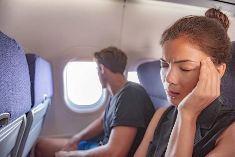 Sick woman on airplane with headache.