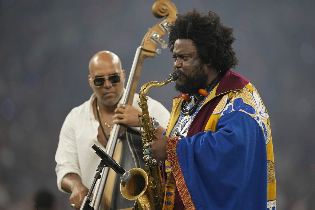 Kamasi Washington performs saxophone on a stage