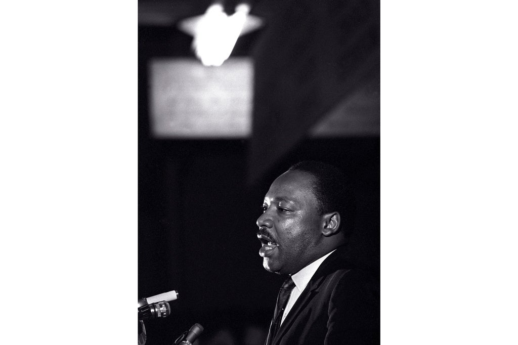 Martin Luther King Jr. speaks into a microphone in a black and white photo