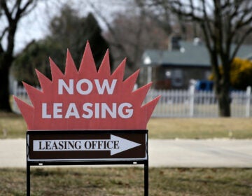 a sign reads NOW LEASING and points to a leasing office
