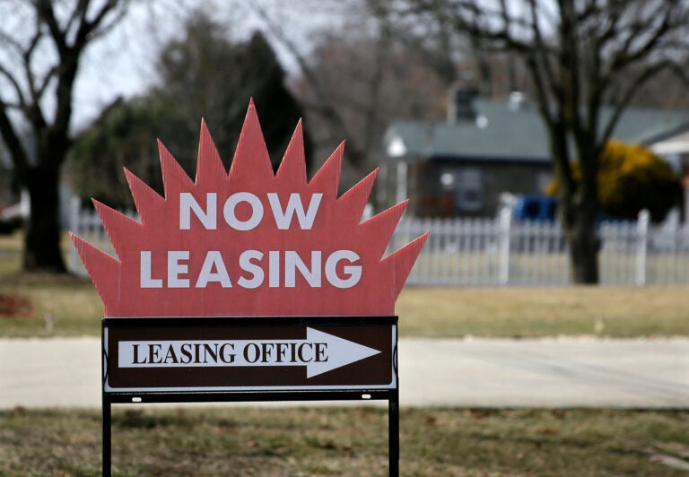 a sign reads NOW LEASING and points to a leasing office