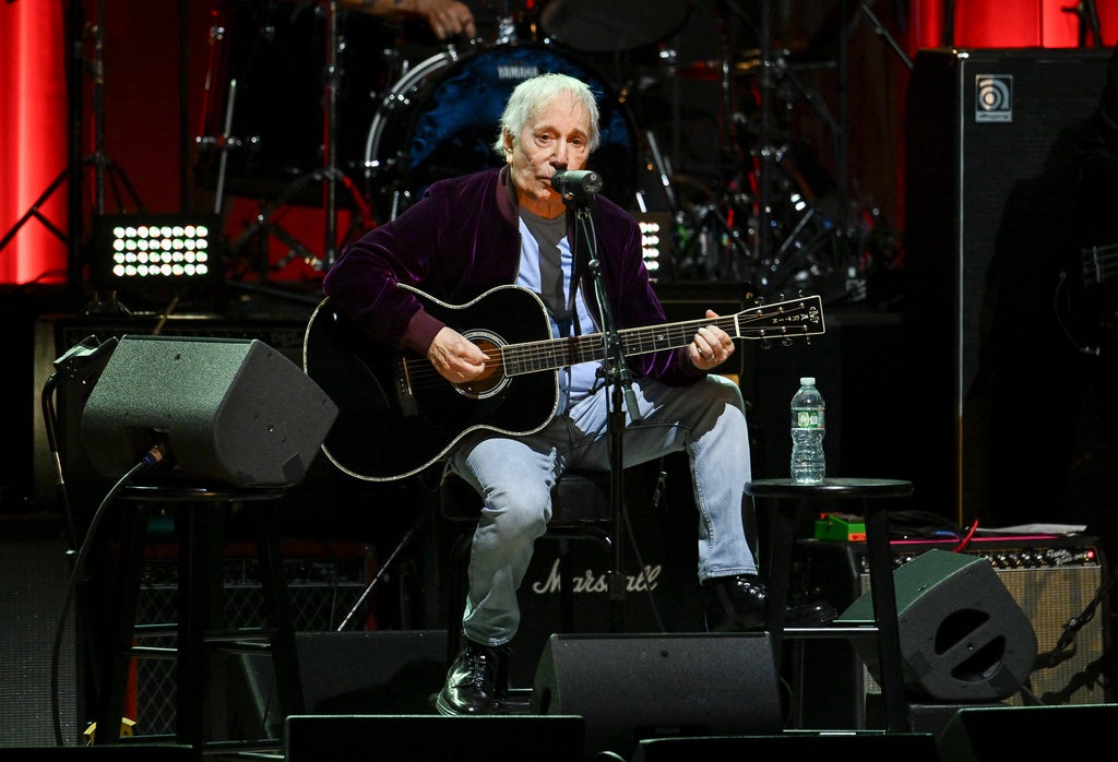 Paul Simon plays guitar on stage